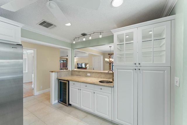 kitchen featuring visible vents, wine cooler, stainless steel fridge, white cabinetry, and a sink