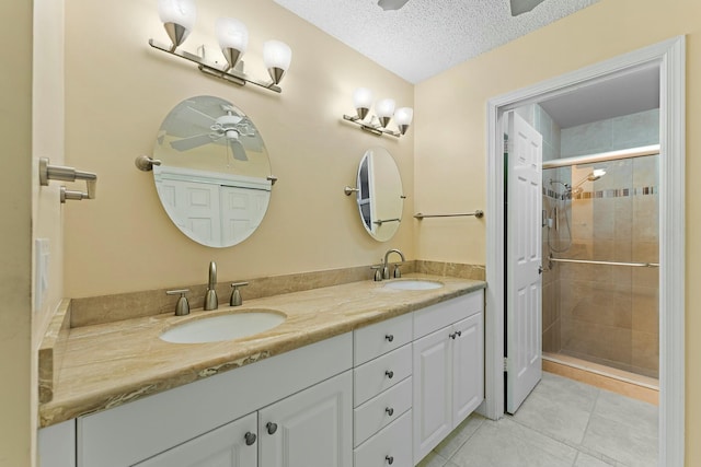 bathroom with a shower stall, a textured ceiling, ceiling fan, and a sink