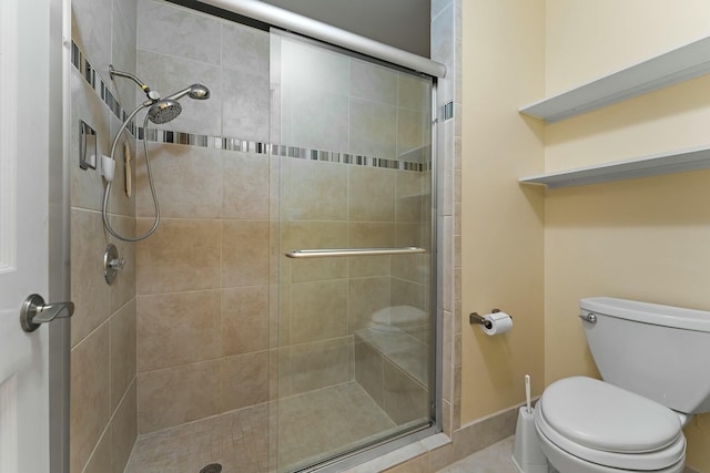 bathroom featuring baseboards, toilet, and a stall shower