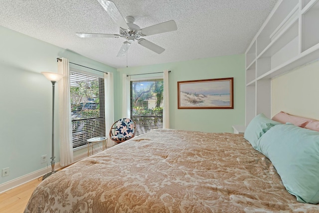 bedroom featuring a textured ceiling, wood finished floors, a ceiling fan, and access to outside