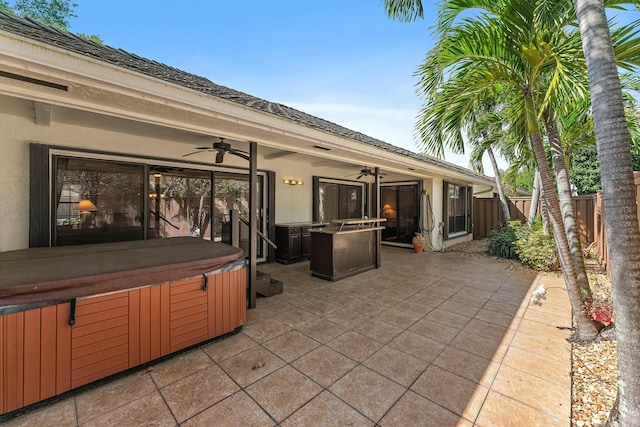 view of patio featuring a hot tub, ceiling fan, and fence