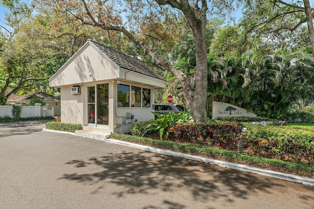 view of front of home featuring a wall mounted air conditioner and fence