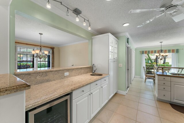 kitchen with wine cooler, ornamental molding, white cabinets, and a sink