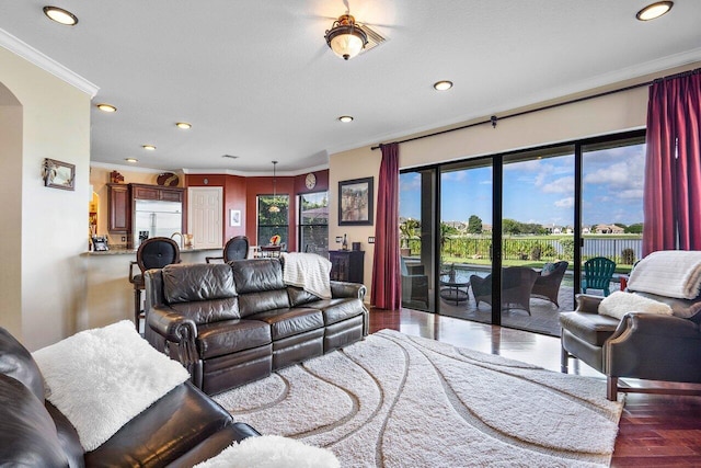 living area with arched walkways, crown molding, recessed lighting, and wood finished floors