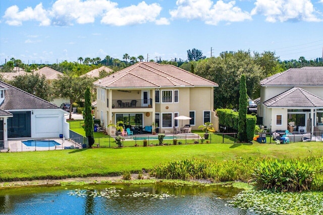 rear view of property featuring a yard, a fenced backyard, a balcony, and a fenced in pool