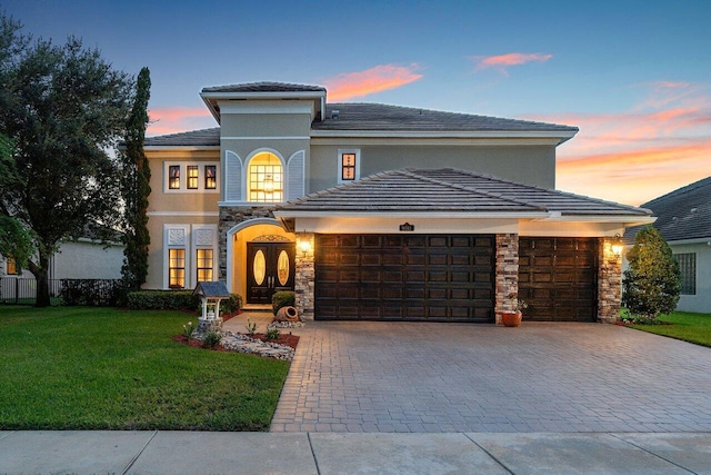 view of front of property with stone siding, decorative driveway, an attached garage, and a front yard