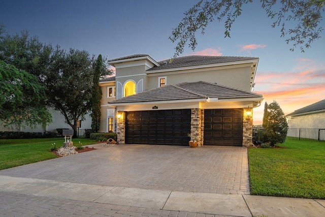 view of front of property with a garage, stone siding, and a lawn