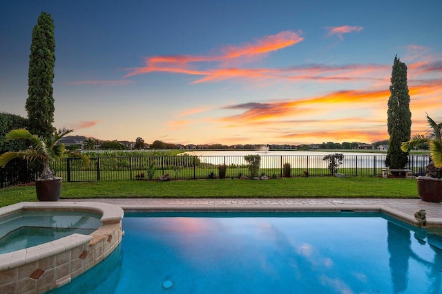 view of swimming pool with a pool with connected hot tub, a water view, a yard, and a fenced backyard