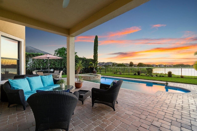 patio terrace at dusk with a pool with connected hot tub, a fenced backyard, and an outdoor living space