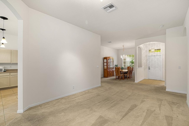 10617 Pine Cone Ln, Fort Pierce, FL 34945 - unfurnished room with light carpet, baseboards, visible vents, arched walkways, and a chandelier