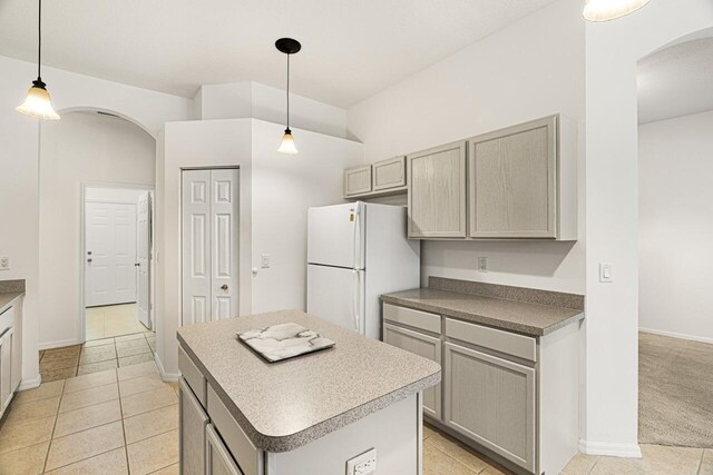 10617 Pine Cone Ln, Fort Pierce, FL 34945 - kitchen featuring arched walkways, gray cabinetry, light carpet, a kitchen island, and freestanding refrigerator