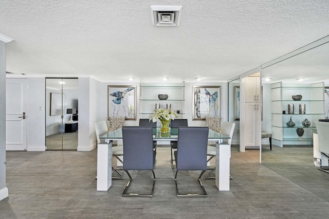 dining space with a textured ceiling, wood finished floors, and baseboards