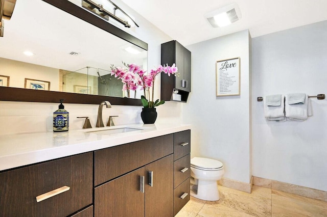 bathroom featuring toilet, vanity, baseboards, visible vents, and a shower with door