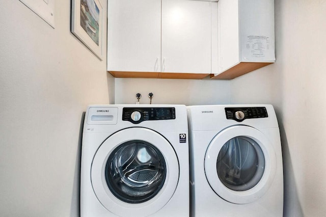 laundry room featuring washing machine and clothes dryer and cabinet space