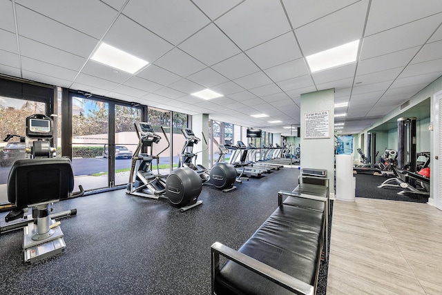 gym with expansive windows, a drop ceiling, and visible vents