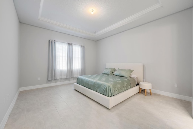 bedroom with a textured ceiling, a tray ceiling, ornamental molding, and baseboards