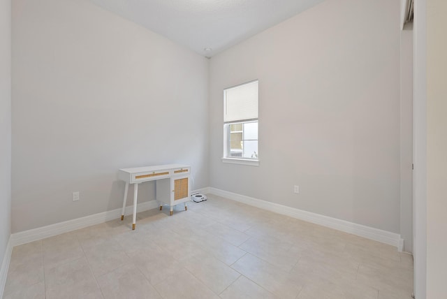 empty room with baseboards and light tile patterned floors