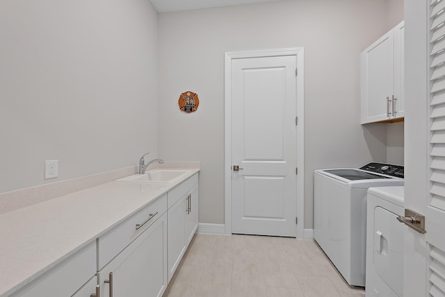 washroom with cabinet space, baseboards, washer and clothes dryer, and a sink