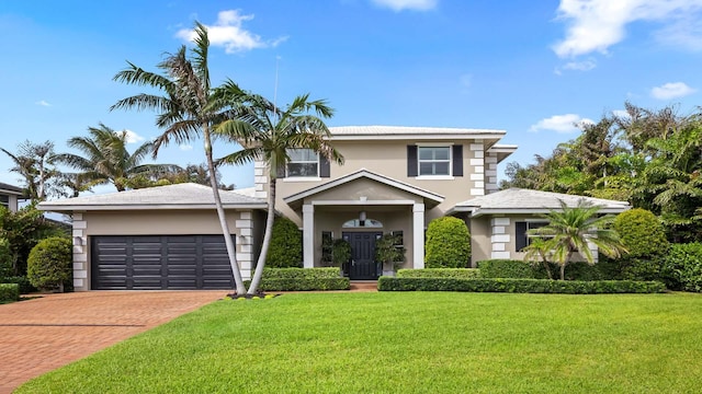 view of front facade with a garage, a front yard, decorative driveway, and stucco siding