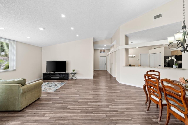 living area featuring a chandelier, a textured ceiling, and wood finished floors