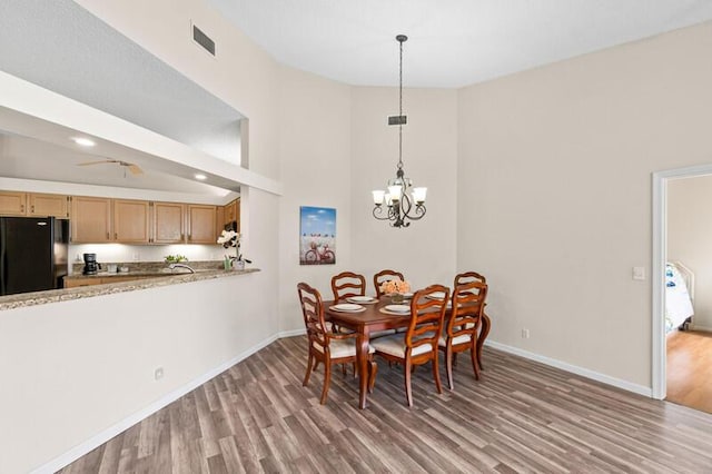 dining area featuring light wood-style floors, visible vents, a notable chandelier, and baseboards