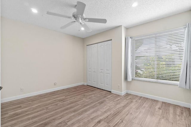 unfurnished bedroom featuring a textured ceiling, wood finished floors, a ceiling fan, baseboards, and a closet