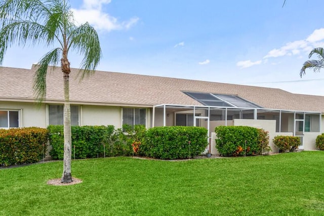 view of front of house featuring a front yard, roof with shingles, and stucco siding