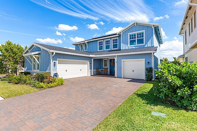 view of front facade featuring board and batten siding, decorative driveway, roof mounted solar panels, and a front lawn