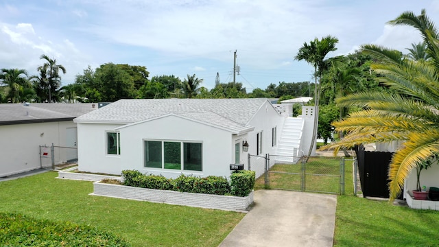 view of front of house featuring a front lawn, fence, a gate, and stucco siding