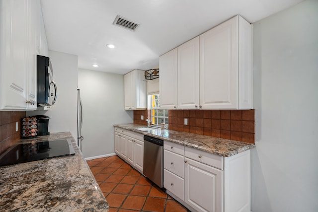 kitchen with white cabinets, visible vents, stainless steel appliances, and decorative backsplash