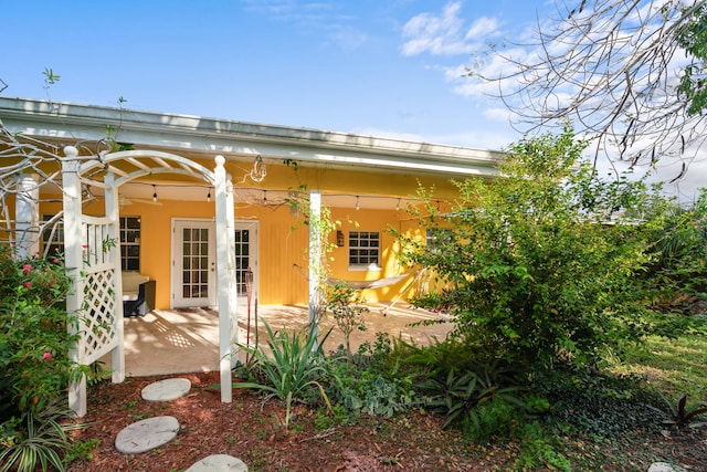 rear view of house with ceiling fan, a patio, and french doors