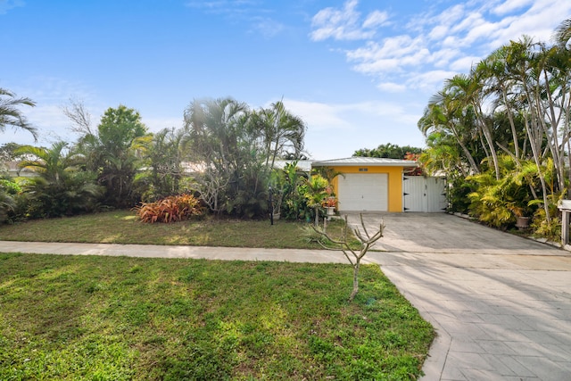 view of front facade with a garage, concrete driveway, a gate, stucco siding, and a front lawn