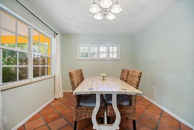 tiled dining room featuring a notable chandelier and baseboards