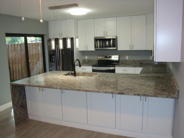 kitchen featuring stone counters, white cabinetry, stainless steel appliances, and a sink