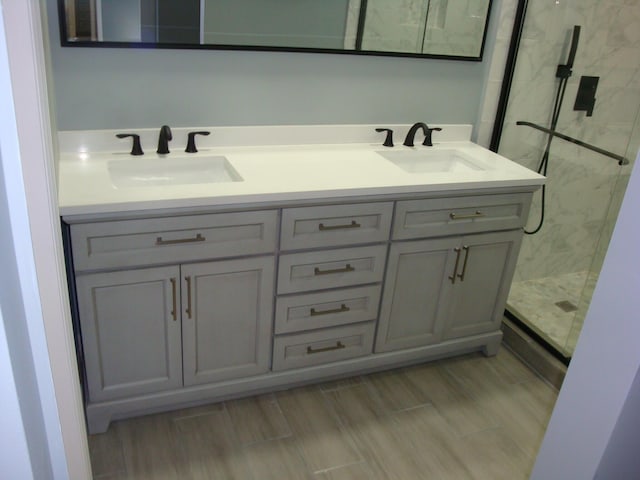 bathroom with double vanity, wood tiled floor, a sink, and a shower stall