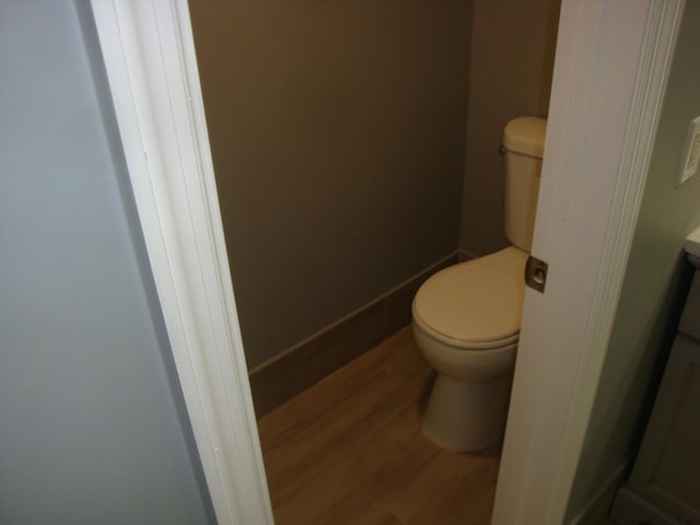 bathroom with toilet, baseboards, and wood finished floors