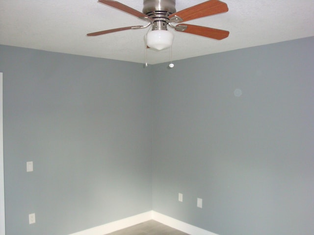 spare room with a ceiling fan and baseboards