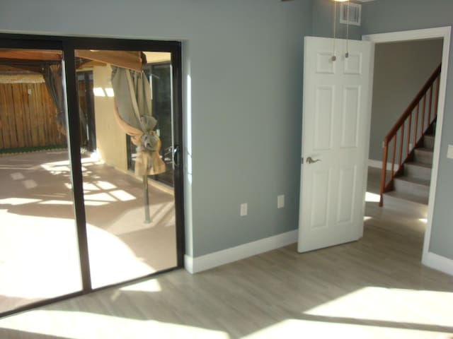 spare room with visible vents, stairway, baseboards, and wood finished floors