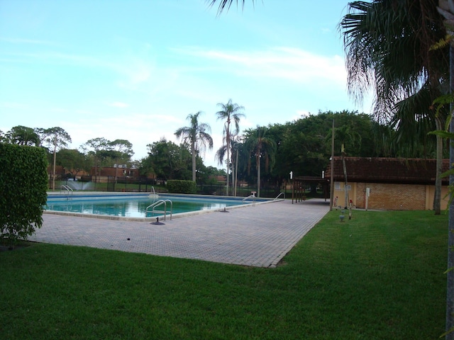 community pool with a lawn and a patio area