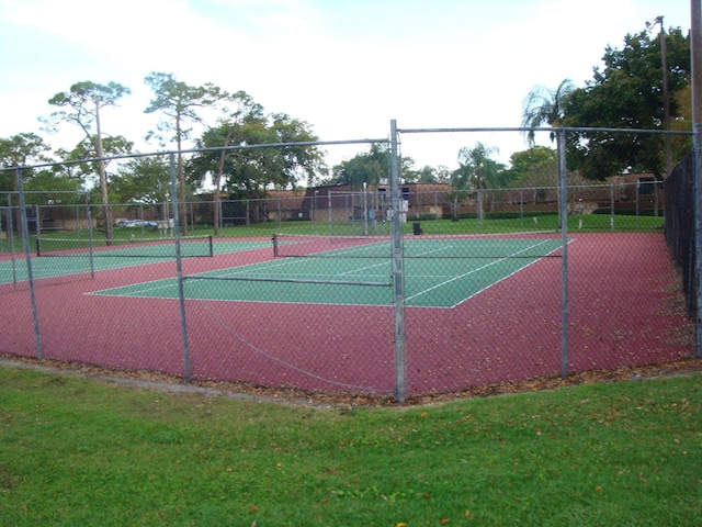 view of tennis court featuring fence and a lawn