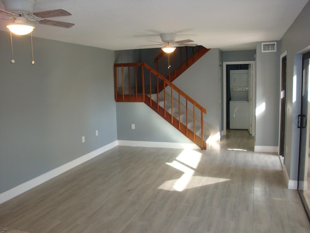 unfurnished living room with stairway, wood finished floors, and baseboards