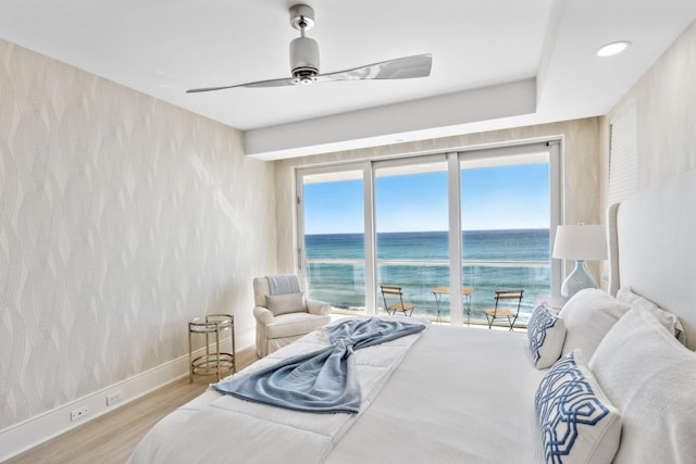 bedroom featuring ceiling fan, baseboards, wood finished floors, and a water view