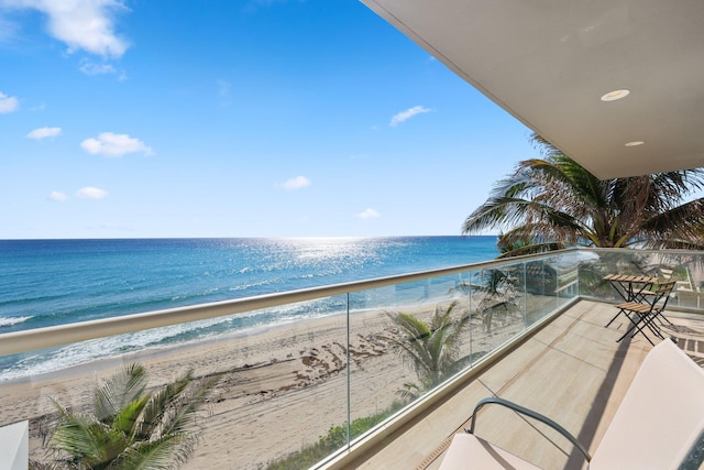 balcony with a water view and a view of the beach