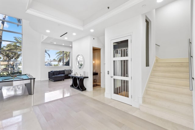 corridor featuring recessed lighting, a raised ceiling, stairs, and crown molding