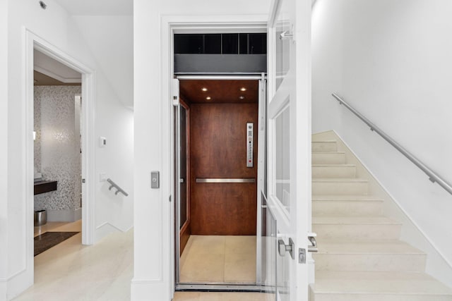 stairway with elevator, tile patterned floors, and wallpapered walls