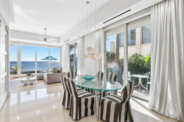 dining area featuring a ceiling fan and a water view