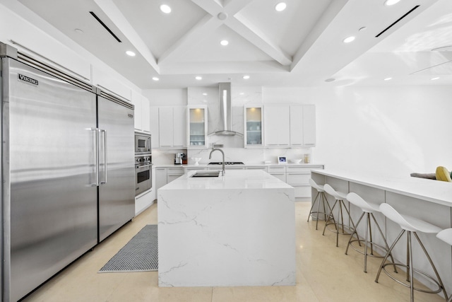 kitchen featuring built in appliances, white cabinetry, wall chimney exhaust hood, and modern cabinets