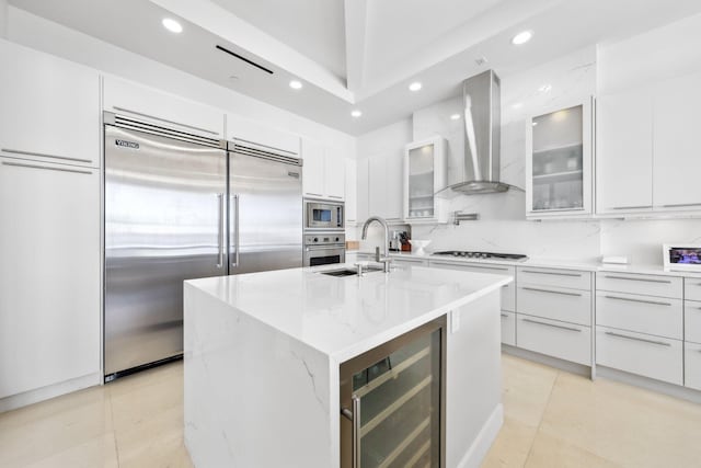 kitchen with a sink, wine cooler, built in appliances, wall chimney range hood, and modern cabinets