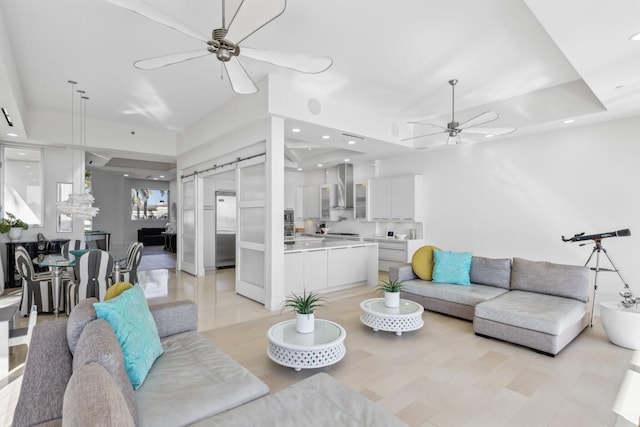 living area featuring recessed lighting, a tray ceiling, and ceiling fan