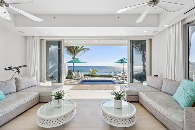 living area featuring recessed lighting, a ceiling fan, and a water view